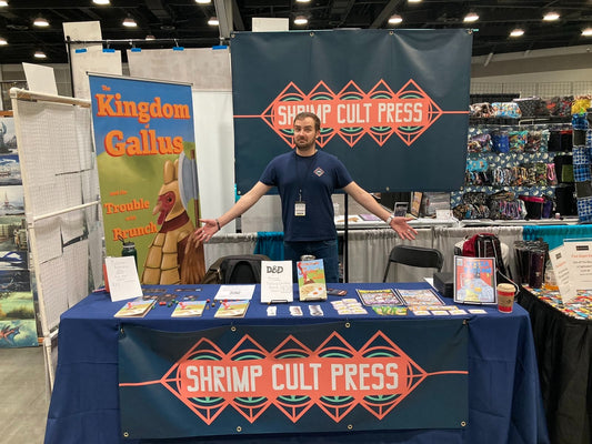 A photo of Shrimp Cult Press founder and independent artist Peter Davoust in front of the SCP booth at Fan Expo Vancouver 2023.