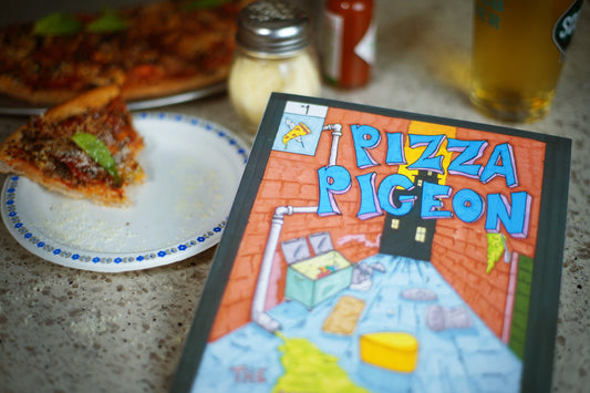 Pizza Pigeon, an indie graphic novel by independent artist Jared Clay. It's in front of a delicious slice of pizza. I know it was delicious because I ate it after I took the photo.